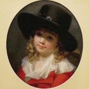 Portrait of a young boy wearing a black hat and red coat